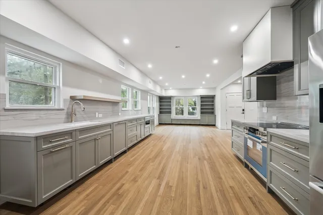 a large kitchen with stainless steel appliances granite countertop a lot of counter space and wooden floors