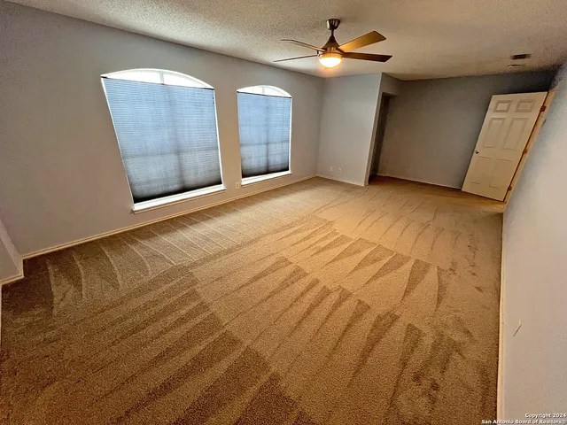 an empty room with windows and fan