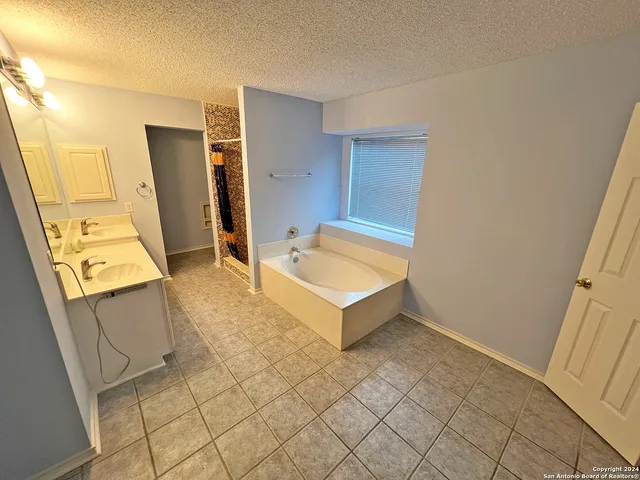 a spacious bathroom with a tub sink and mirror
