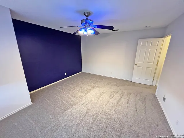 a view of an empty room with a chandelier fan