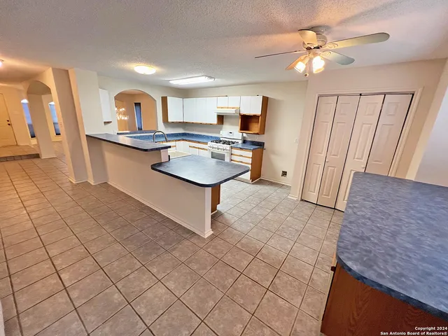 a view of a kitchen with kitchen island granite countertop a sink and a stove top oven