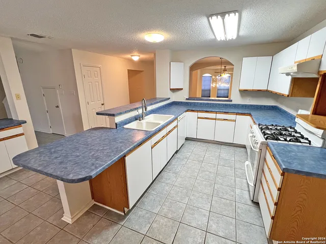 a large kitchen with kitchen island a sink a counter space and a view of living room