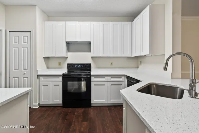 a kitchen with granite countertop white cabinets and white appliances