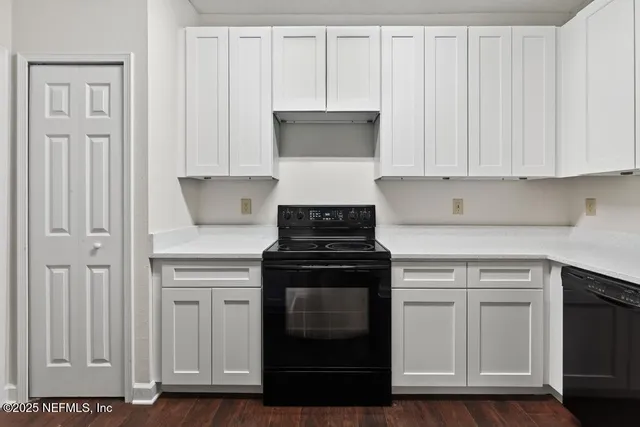 a kitchen with white cabinets and black appliances