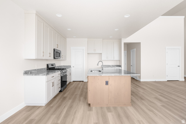 1510 West 600 North, Unit GE 04 Mapleton, UT 84664 - Photo 11 of 21 Open-concept kitchen featuring an island with an integrated sink, white cabinetry, a stainless steel microwave and range, and speckled countertops