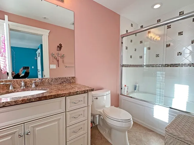 a bathroom with a granite countertop sink a toilet and shower