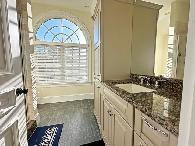 a bathroom with a granite countertop sink a vanity a mirror and a bathtub