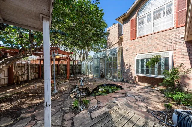 a backyard of a house with plants and large tree