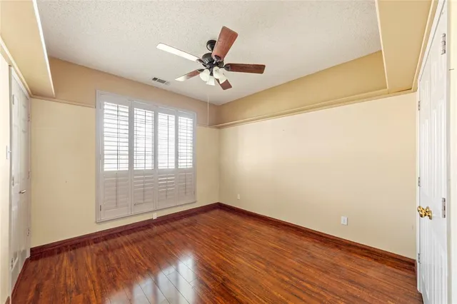 an empty room with wooden floor fan and windows