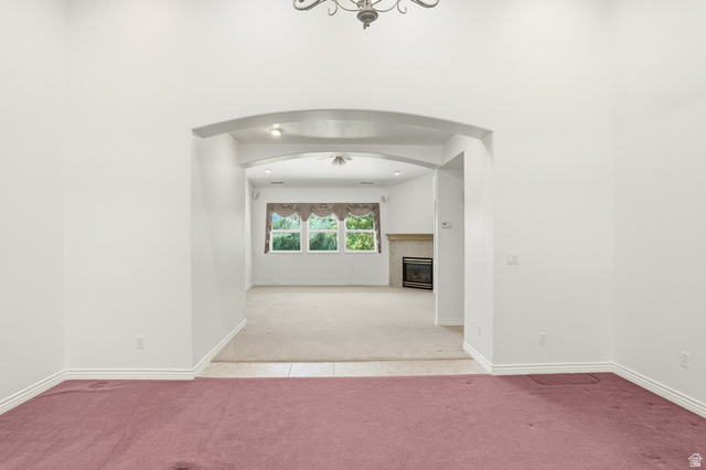 2190 750 West Perry, UT 84302 - Photo 10 of 42 Archway entry from a carpeted room into a living space featuring a fireplace with a stone surround, multiple windows, and a ceiling fan