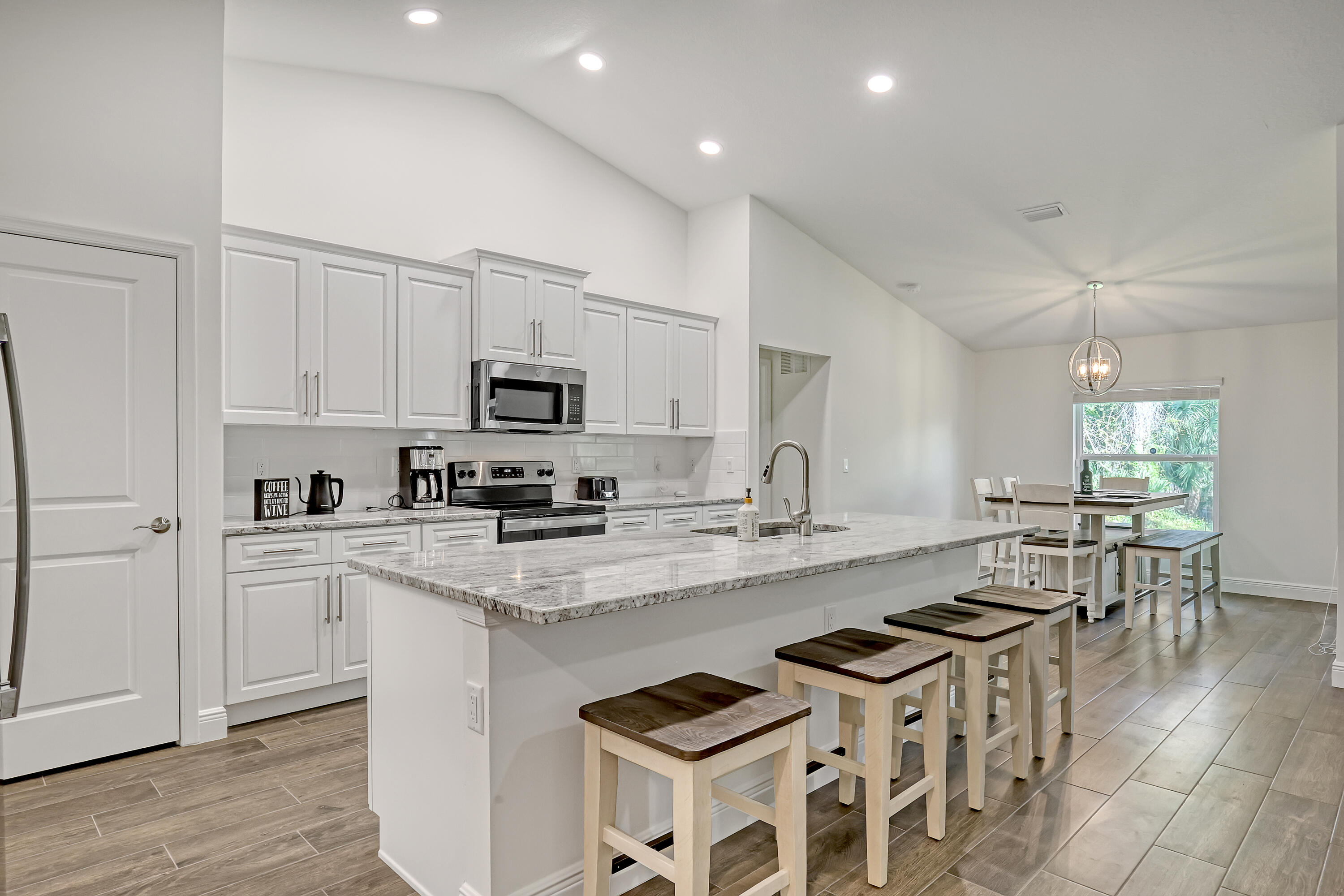 16775 Orange Boulevard Loxahatchee, FL 33470 - Photo 14 of 53 a kitchen with stainless steel appliances granite countertop a stove top oven a sink a refrigerator white cabinets and wooden floor