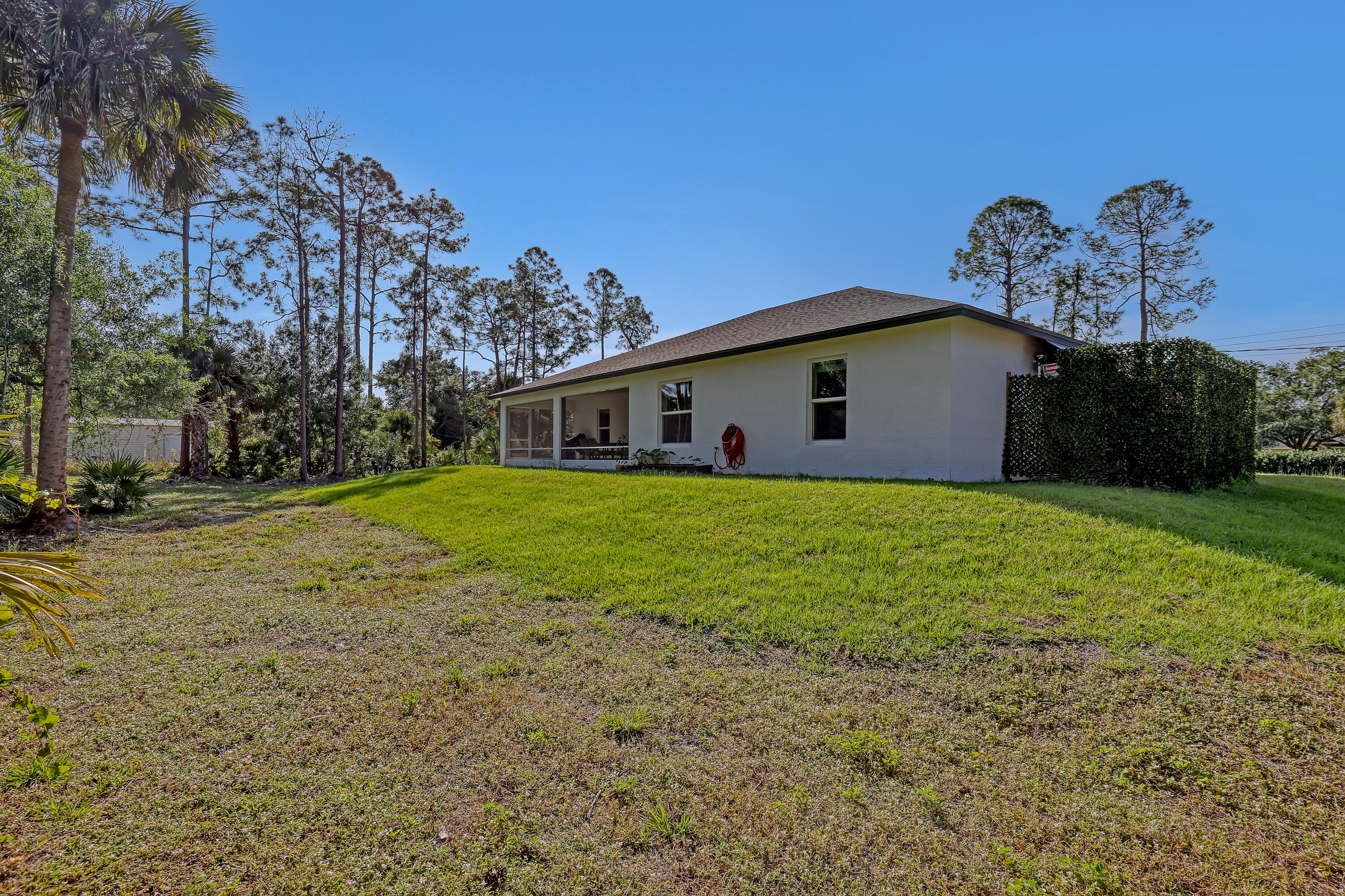 16775 Orange Boulevard Loxahatchee, FL 33470 - Photo 48 of 53 a white house that has a big yard with wooden fence