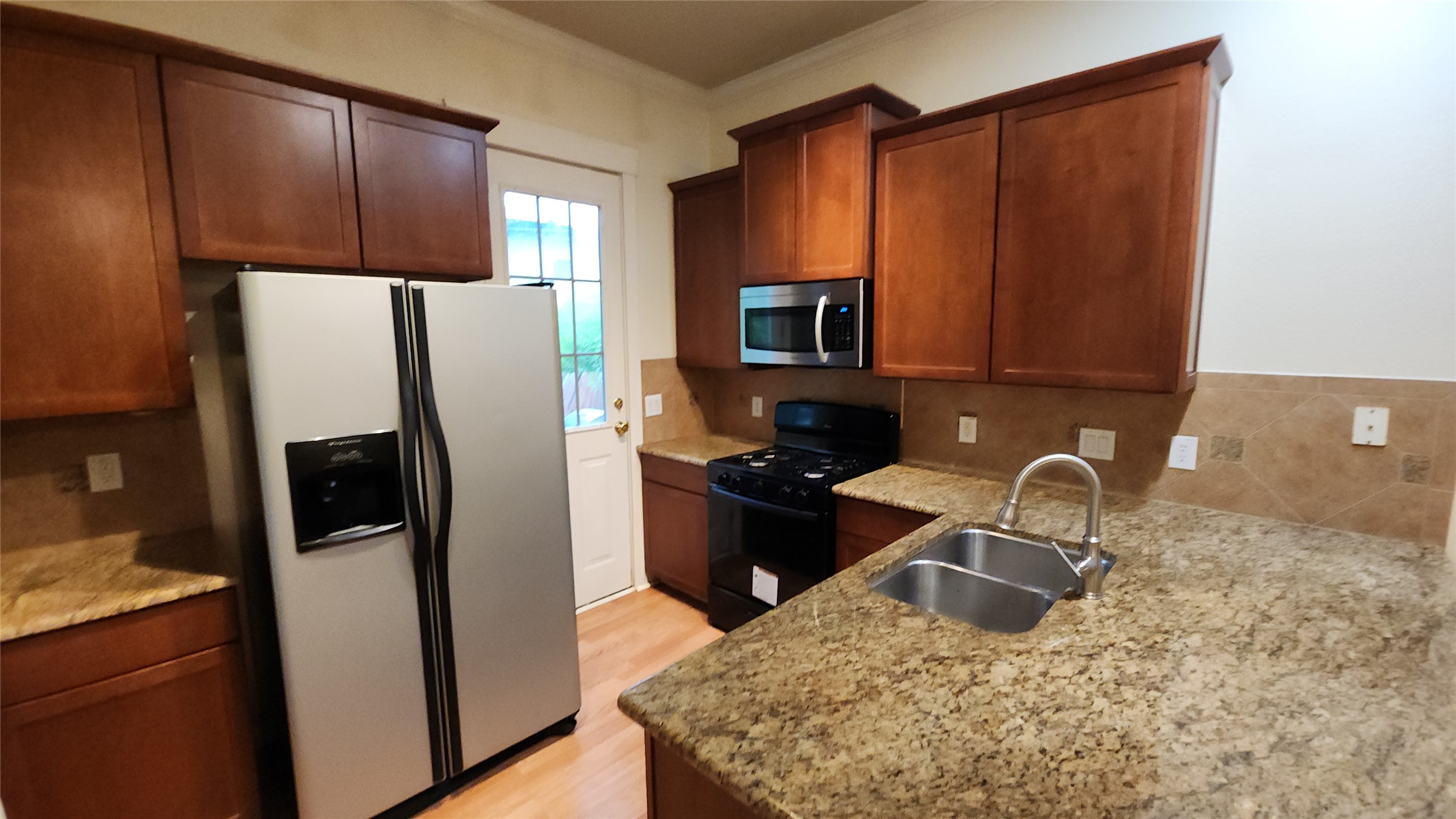 611 Franklin Boulevard, Unit B Austin, TX 78751 - Photo 1 of 3 a kitchen with granite countertop wooden cabinets a refrigerator and a sink