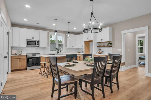 a view of a dining room and livingroom with furniture wooden floor a chandelier