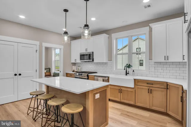 a kitchen with stainless steel appliances granite countertop a sink a stove a refrigerator cabinets and chairs