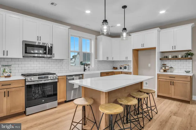 a kitchen with cabinets a sink stainless steel appliances and wooden floor