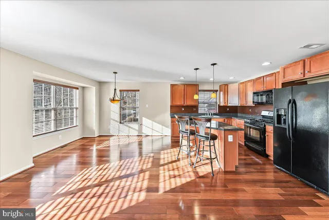 a view of a kitchen with kitchen island stainless steel appliances wooden floor and a window