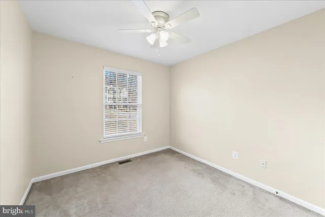 an empty room with a window and a ceiling fan