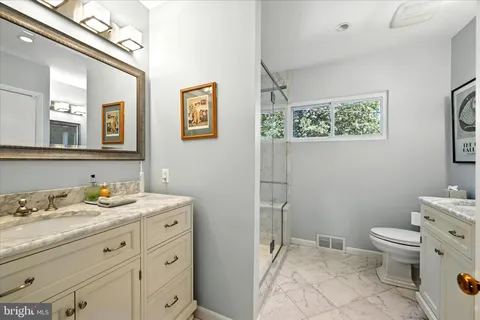 a bathroom with a granite countertop sink mirror and toilet