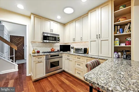 a kitchen with stainless steel appliances granite countertop a stove top oven a sink and a refrigerator