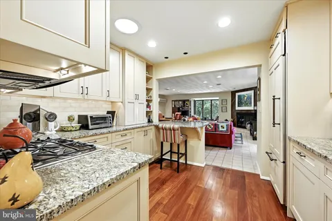 a kitchen with stainless steel appliances granite countertop sink stove refrigerator and wooden floor