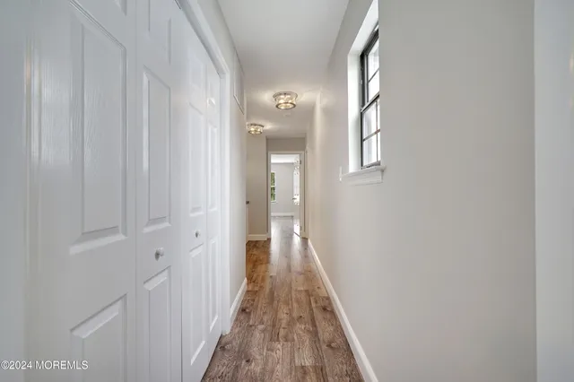 a view of a hallway with wooden floor and a bathroom