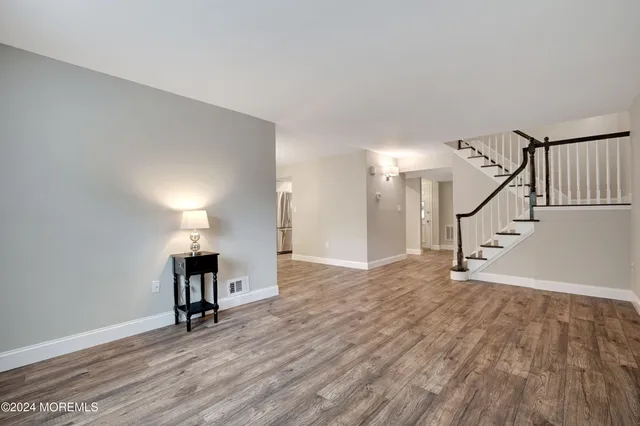 a view of empty room with stairs and wooden floor