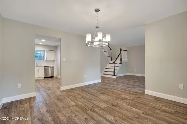 a view of a room with wooden floor staircase and a kitchen