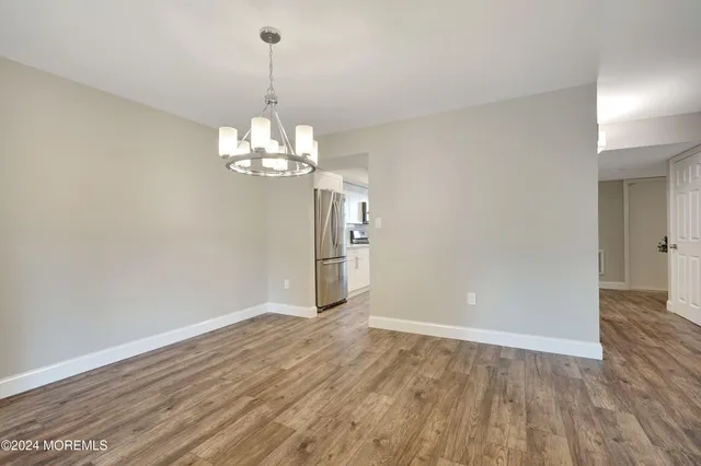 a view of a chandelier in big room with wooden floor and chandelier