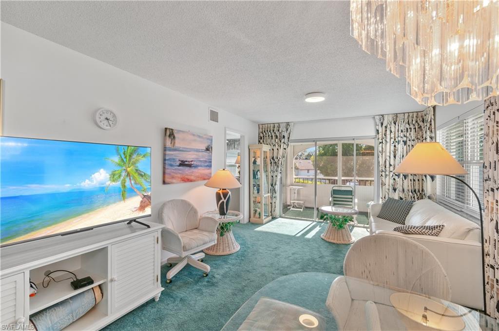5 High Point Circle West, Unit 301 Naples, FL 34103 - Photo 2 of 37 a living room with furniture and a lamp