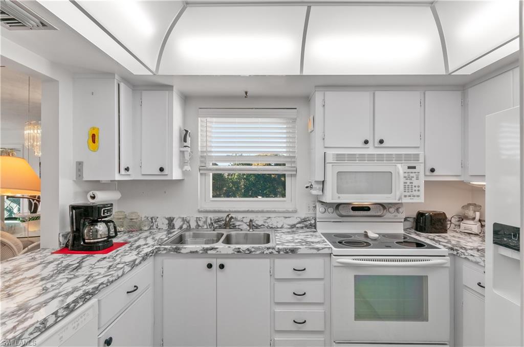 5 High Point Circle West, Unit 301 Naples, FL 34103 - Photo 3 of 37 a kitchen with granite countertop a sink stove and cabinets