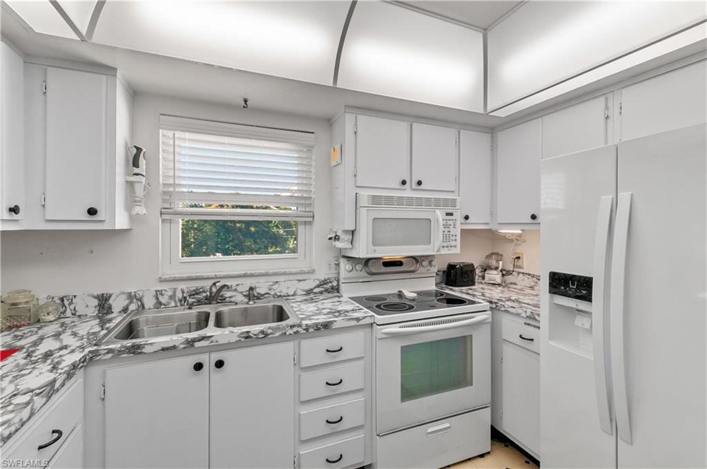 5 High Point Circle West, Unit 301 Naples, FL 34103 - Photo 6 of 37 a kitchen with white cabinets sink and white appliances