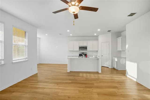 a kitchen with a sink dishwasher a dining table and chairs with wooden floor