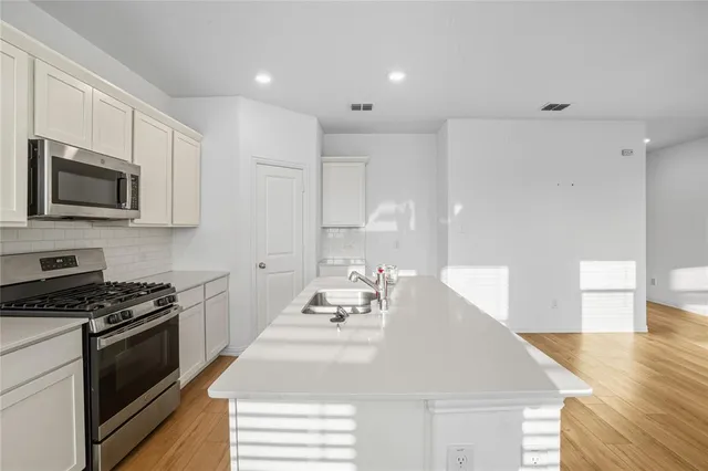 a view of a kitchen with kitchen island wooden floors appliances and cabinets