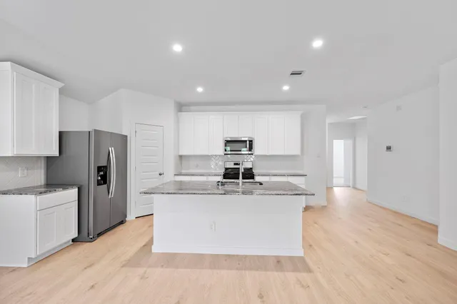 a large kitchen with stainless steel appliances lots of counter space and a refrigerator