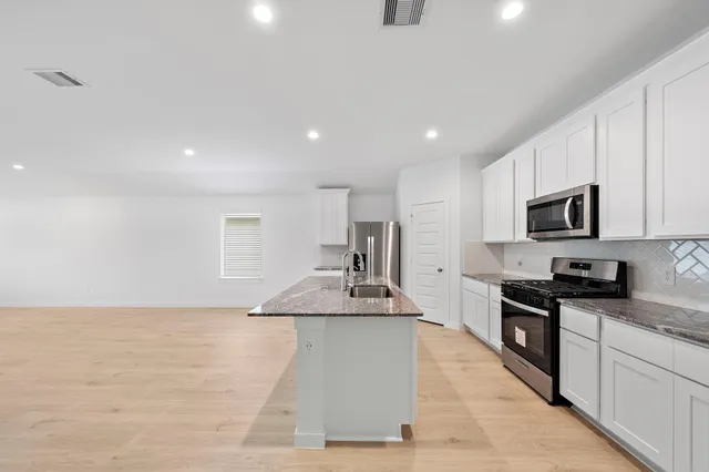 a large kitchen with granite countertop a large counter top stainless steel appliances and cabinets