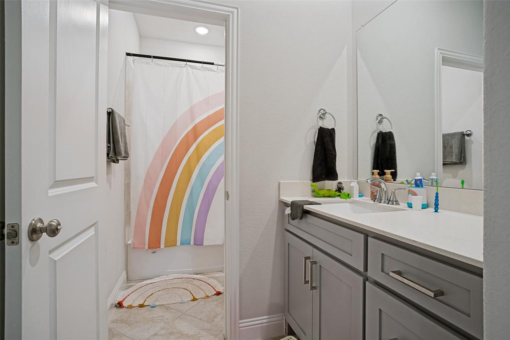 3115 Giovanni Point Princeton, TX 75407 - Photo 21 of 26 Bathroom featuring a single vanity with a white countertop and a rectangular undermount sink, a large wall-mounted mirror, and a built-in bathtub with an overhead shower
