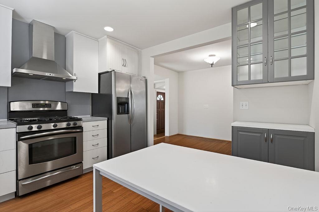 6 Winterberry Road Fishkill, NY 12524 - Photo 16 of 43 Modern kitchen featuring stainless steel appliances, a range hood, white cabinetry, and wood-finish flooring