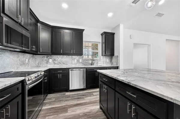 a kitchen with stainless steel appliances granite countertop a sink stove and cabinets