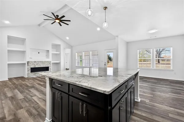 a kitchen with granite countertop center island a wooden floor stainless steel appliances and living room view