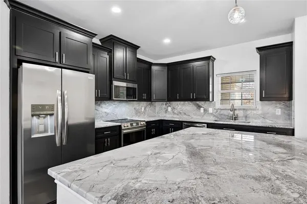 a large kitchen with stainless steel appliances granite countertop a sink a stove and a refrigerator