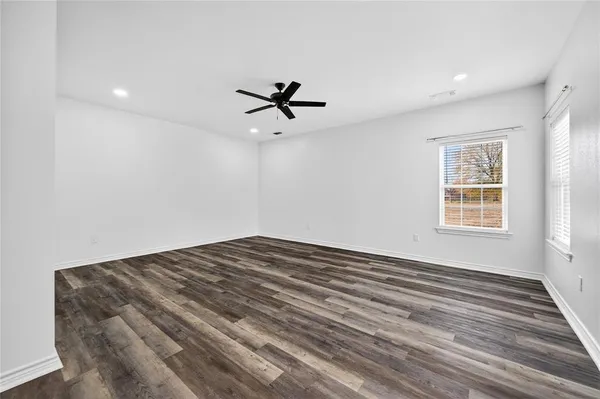 a view of a room with a ceiling fan and hardwood floor