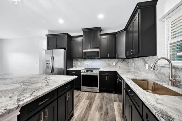 a kitchen with stainless steel appliances granite countertop a sink stove and refrigerator