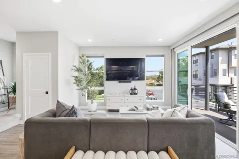 a living room with furniture a flat screen tv and a floor to ceiling window