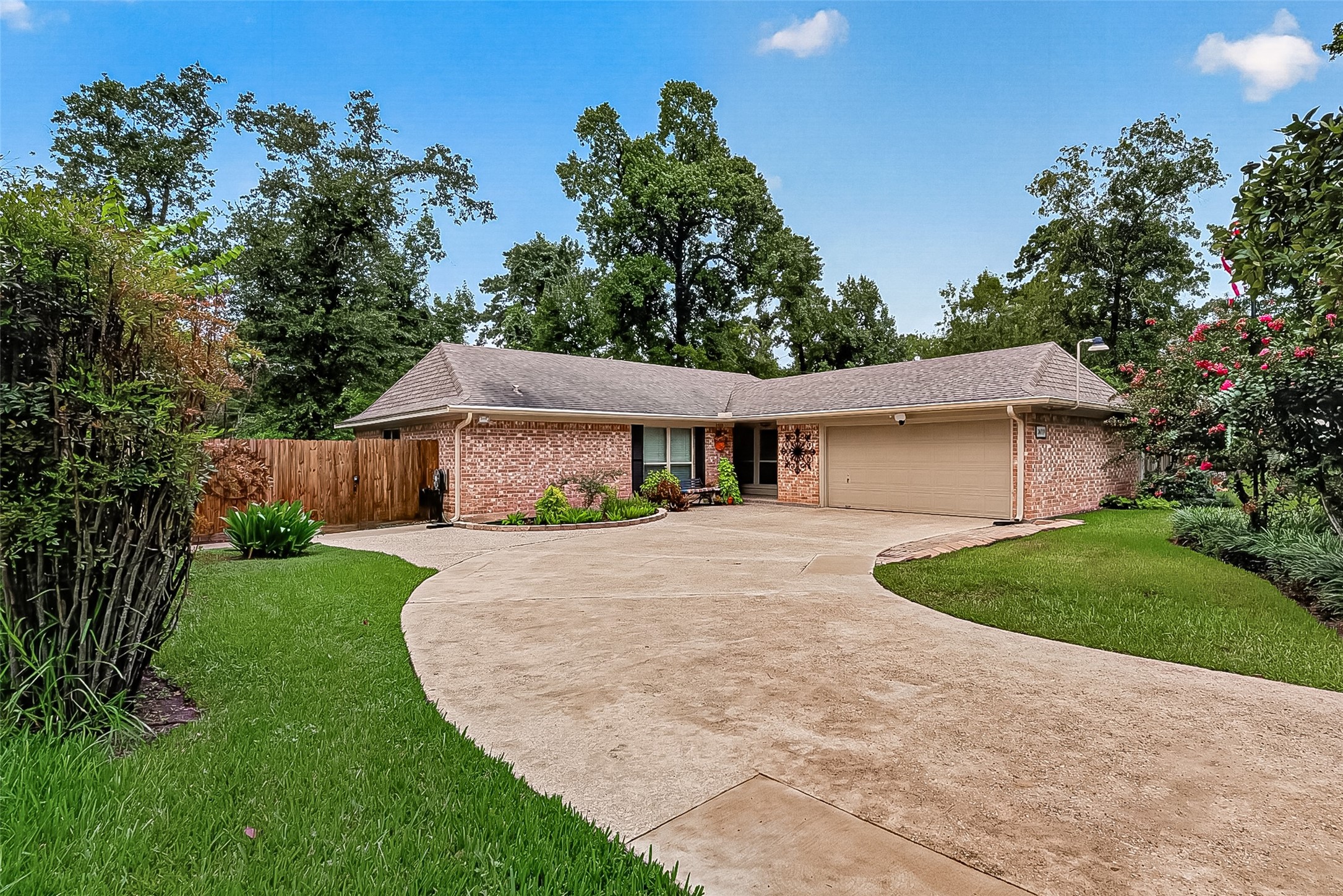 24719 Wilderness Road Spring, TX 77380 - Photo 1 of 42 Charming brick home with a spacious driveway and two-car garage. The front yard features well-maintained landscaping and mature trees, offering a welcoming and serene setting.