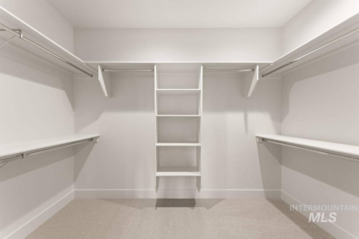 13338 North Spring Creek Way Boise, ID 83714 - Photo 23 of 46 Walk-in closet featuring light beige carpeting, white walls, and extensive built-in shelving