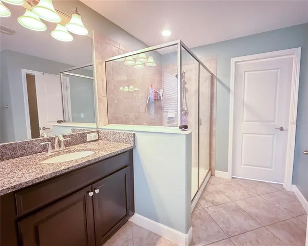 a bathroom with a granite countertop sink a mirror and a shower
