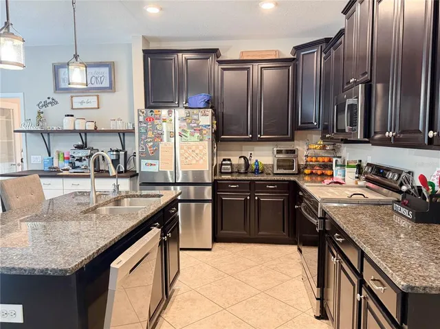 a kitchen with stainless steel appliances granite countertop a sink stove refrigerator and cabinets