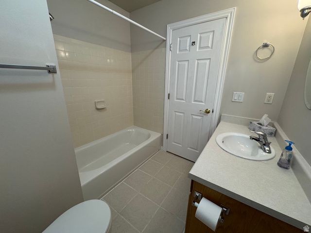 88 Canterbury Lane Logan, UT 84321 - Photo 10 of 37 Bathroom featuring a white bathtub with tiled surround, a white vanity with an integrated sink, and wood-finish cabinetry