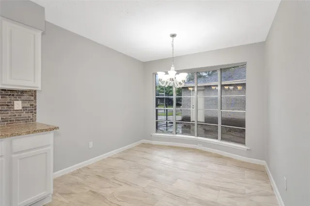 an empty room with chandelier fan and windows